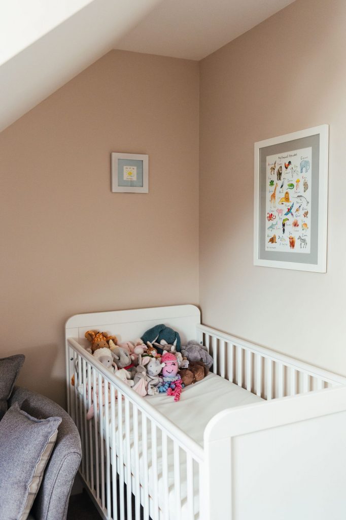 White baby cot filled with stuffed toys