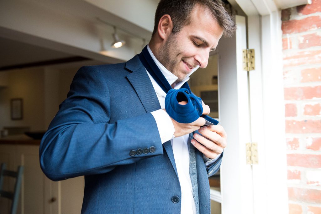 Groom does his tie up on the morning of the wedding