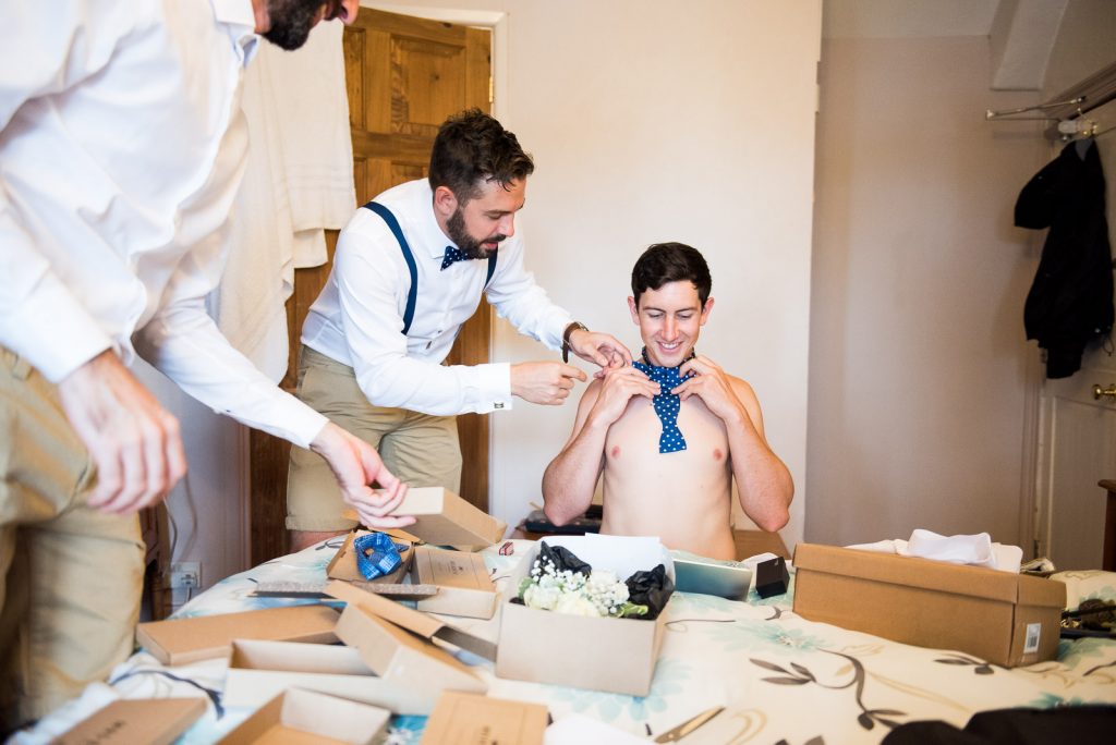 groom preparation photography, groomsmen learn how to tie a bow tie