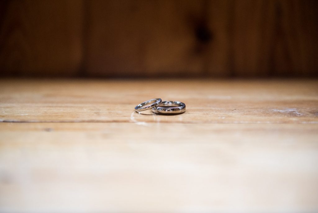 wedding rings placed together on wooden surface, groom preparation photography
