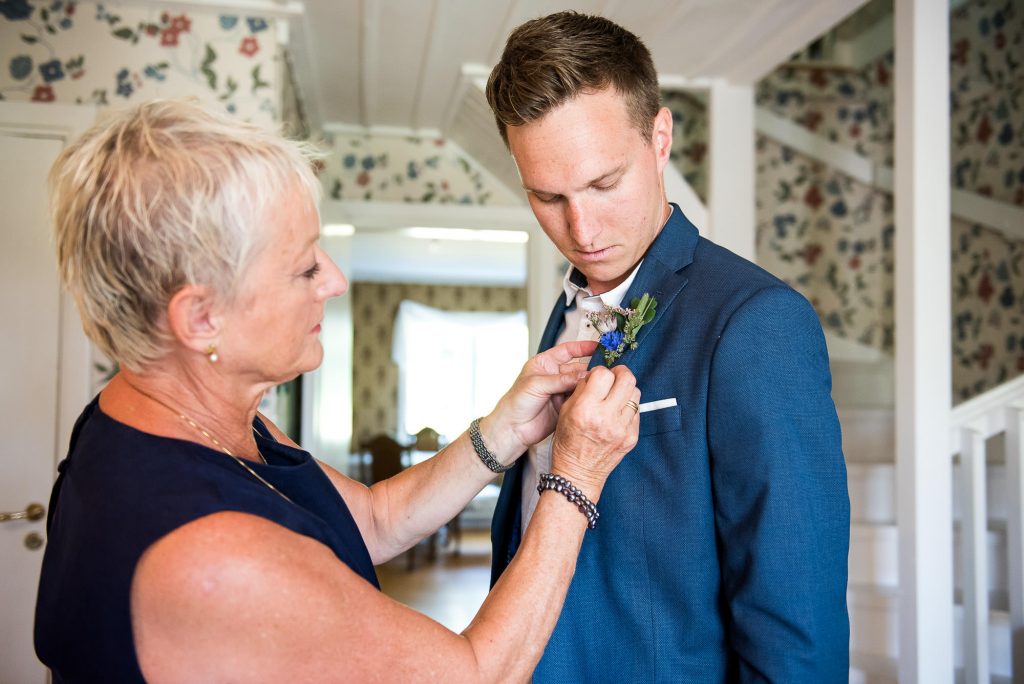 groom preparation photography, mother attaches button hole to son