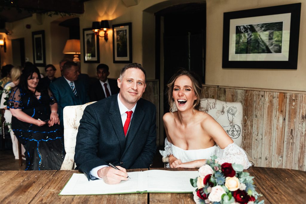 Joyous bride and groom sign their wedding register