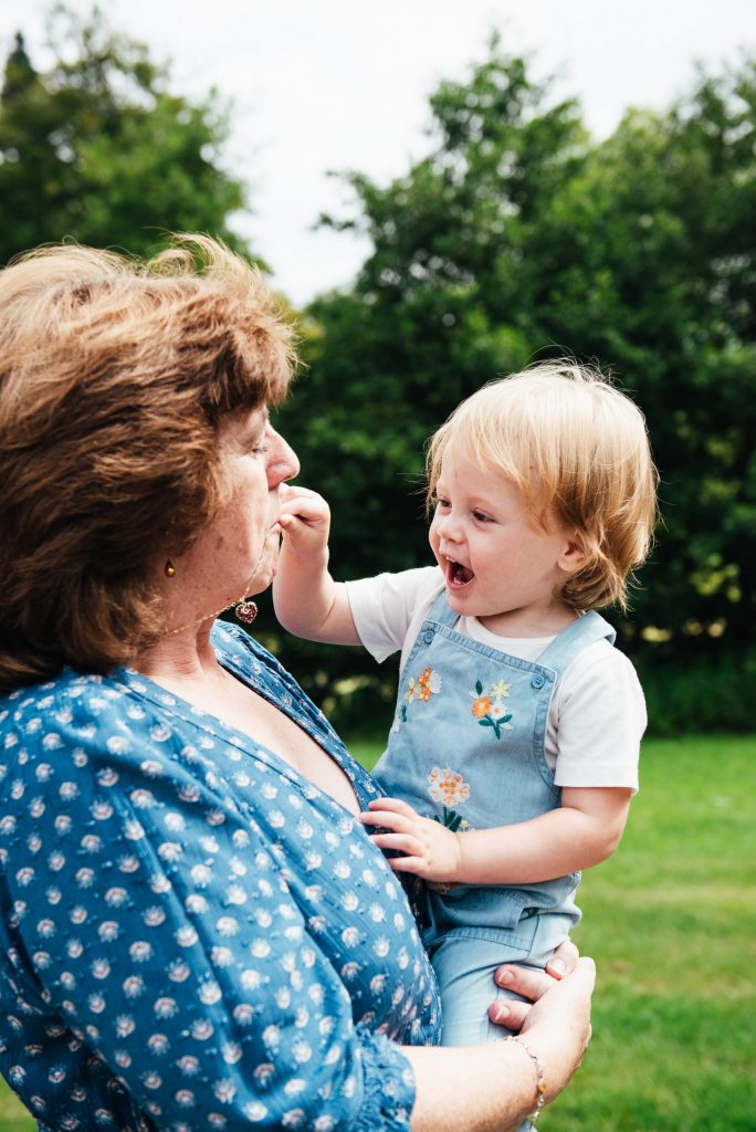 Virginia Water Family Photography, Grandmother and grandchild laugh towards the camera