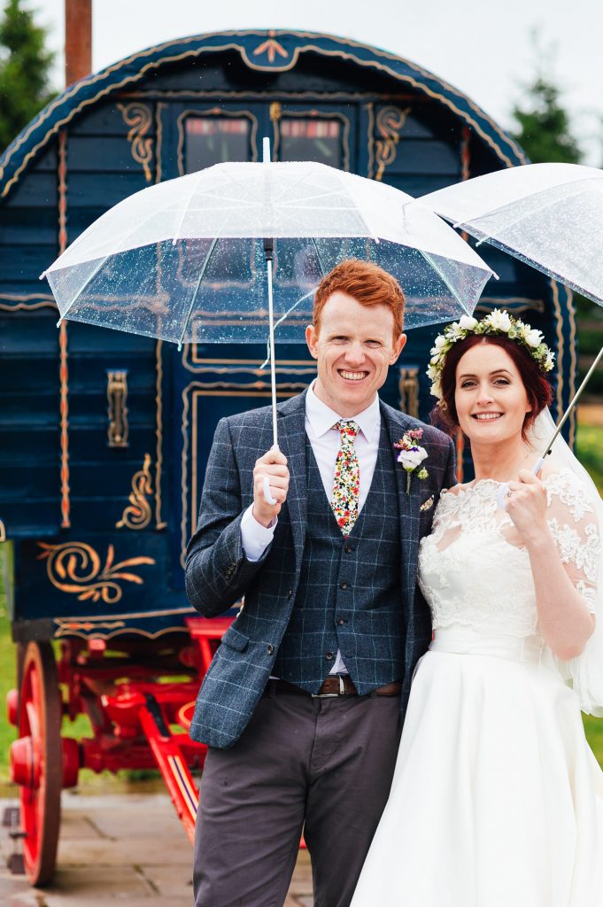 Couple stand with umbrellas outside, rainy yorkshire wedding photography 