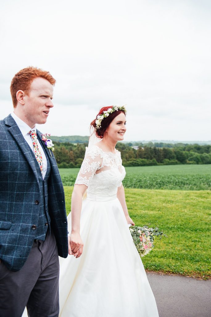 Bride and groom walk hand in had at Deepdale Farm wedding