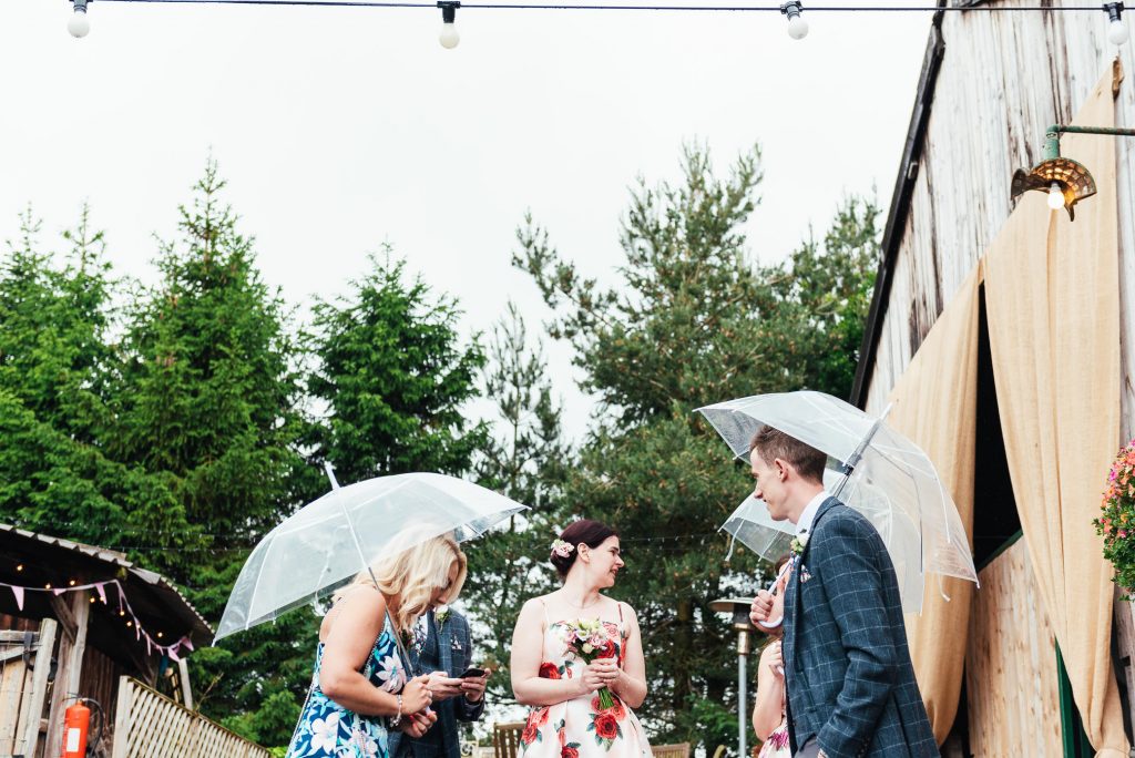 Guests hide under umbrellas for rainy Yorkshire wedding