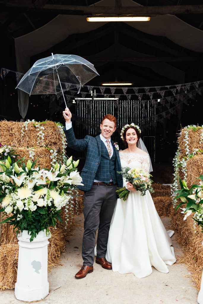Bride and groom pose with umbrella for their Deepdale Farm wedding 