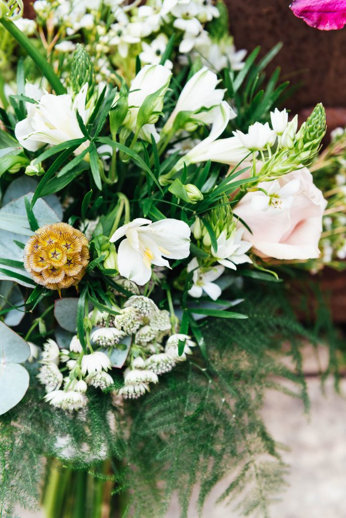 Wedding bouquet arranged with white flowers and green foliage 