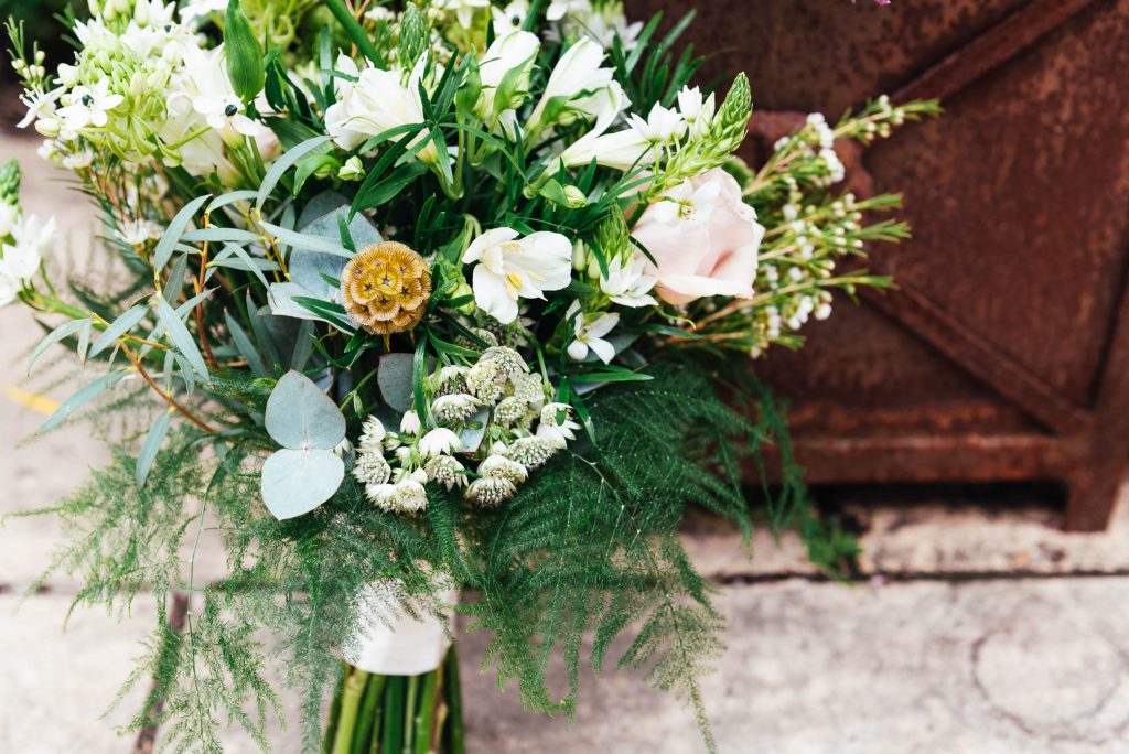 Wedding bouquet arranged with white flowers and green foliage 