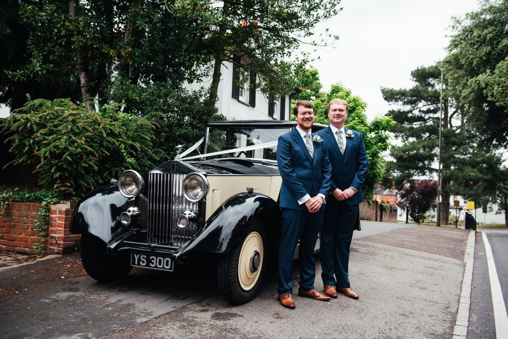 Groom and best man stand with Vintage wedding car