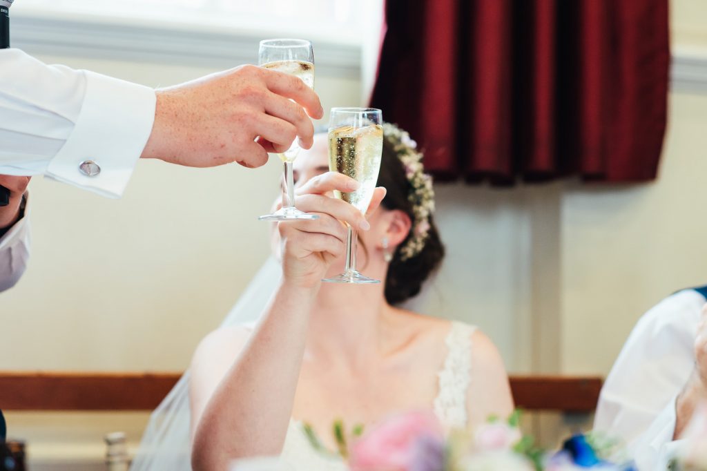 Glasses touch in a cheers during wedding speeches
