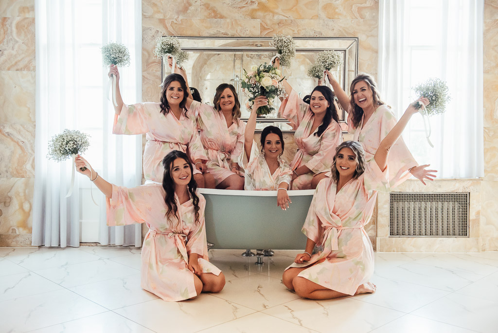 Bride and her bridesmaids pose in the grand bath tub