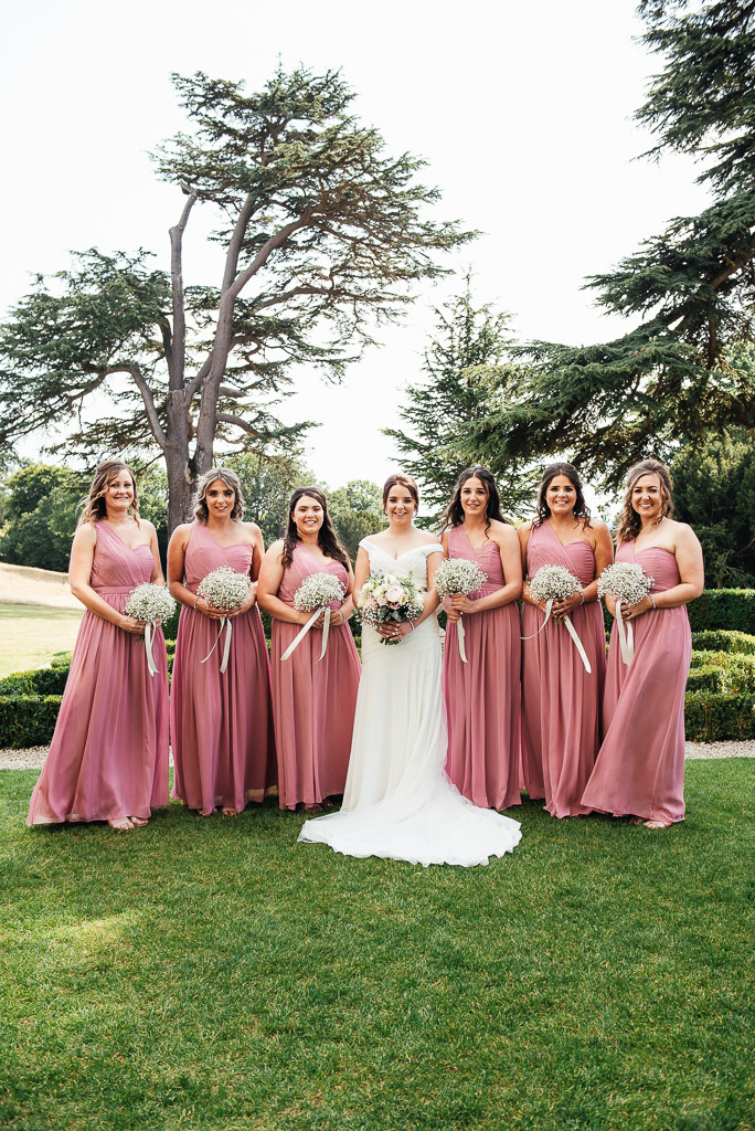 Beautiful bridal party in pastel pink long dresses with matching gypsophila bouquets 