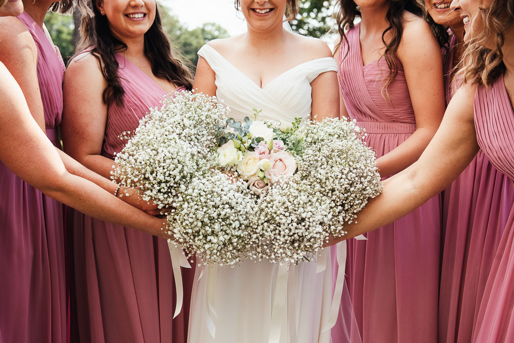 Beautiful bridal party in pastel pink long dresses with matching gypsophila bouquets 