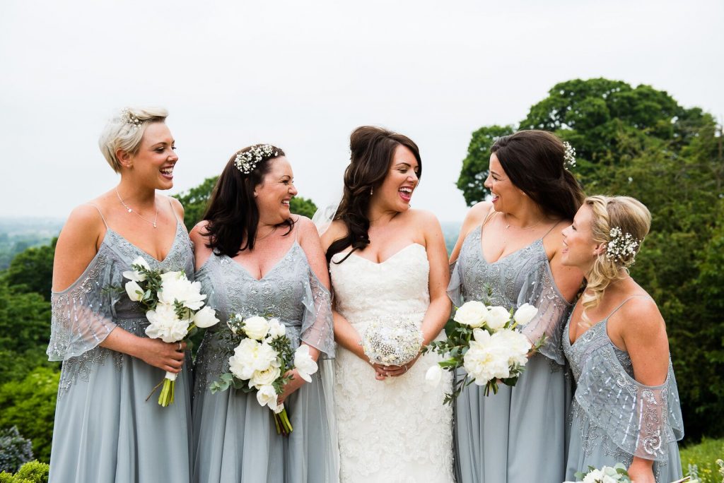 Beautiful bride and her bridesmaids naturally laugh and smile together