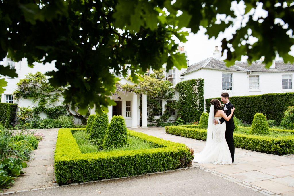 Couple embrace in front of Pembroke Lodge House