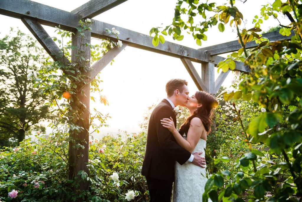 Couple kiss in the rose garden at sunset at Pembroke Lodge