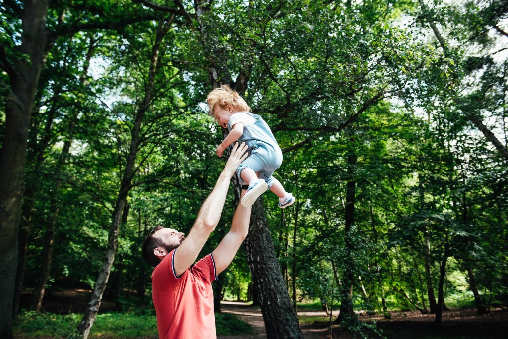 Father playfully throws his daughter up in the air on an outdoor family photoshoot 