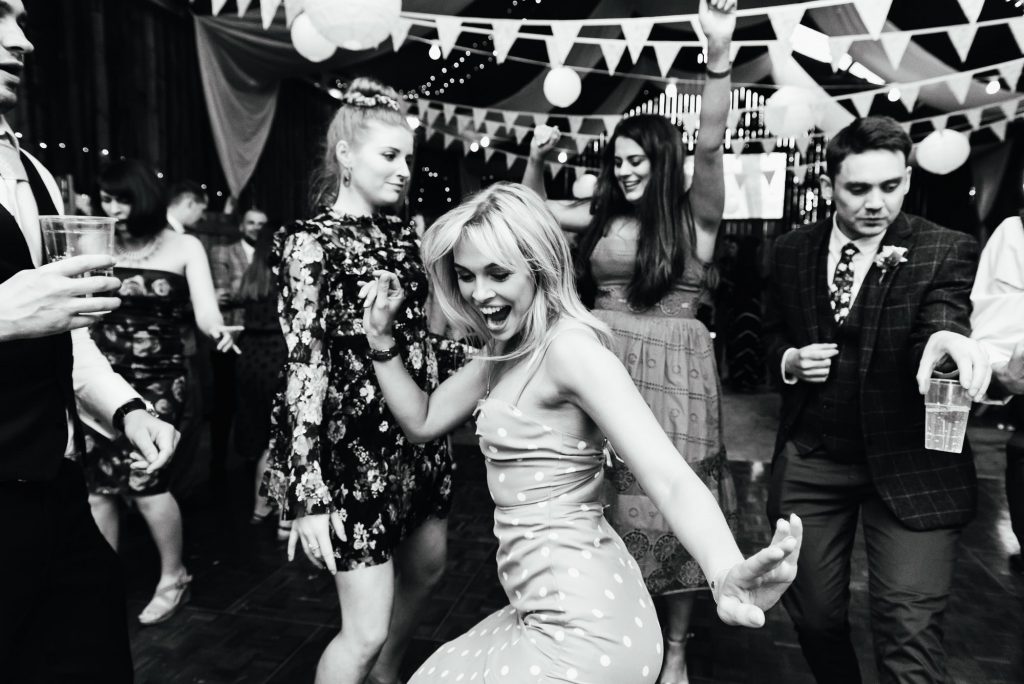 Young woman dances joyfully at a rustic barn wedding