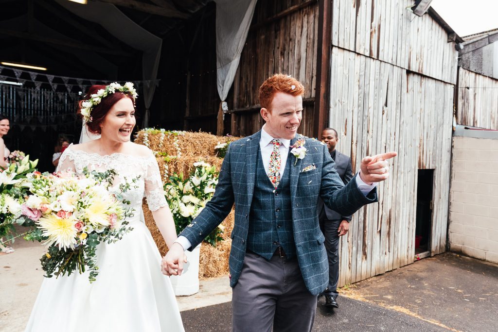 Outdoor wedding photography, couple walk outside their rustic barn wedding