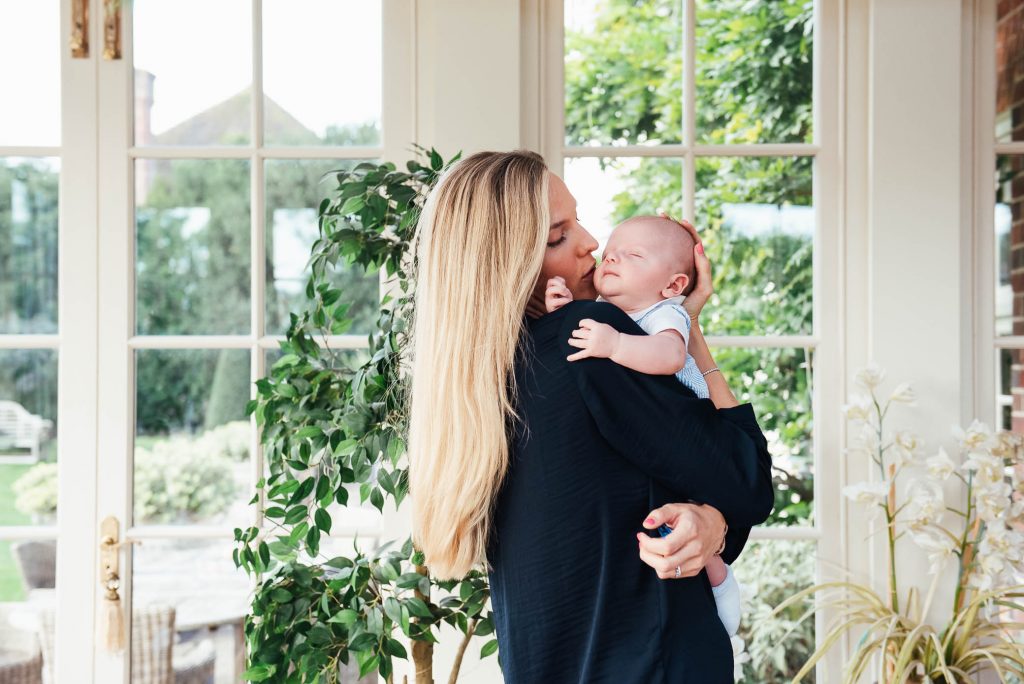 Mother lovingly holds her child in light and airy conservatory