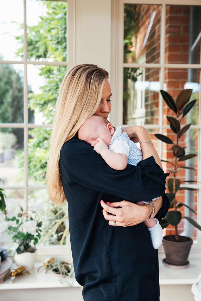 Mother lovingly holds her child in light and airy conservatory