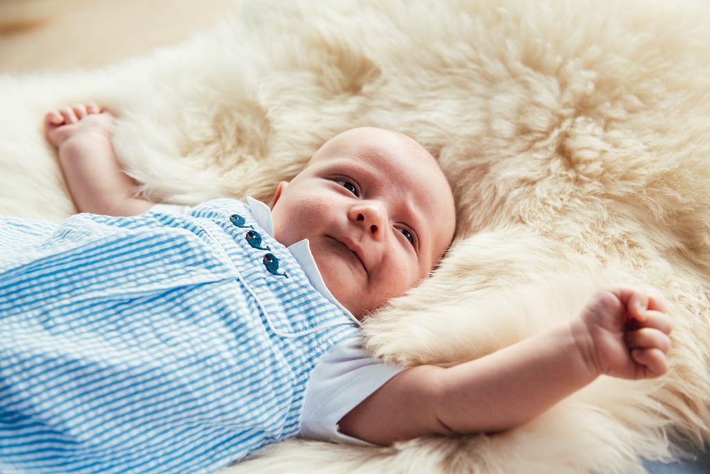 Newborn baby sleeps on a sheepskin rug and stretches 