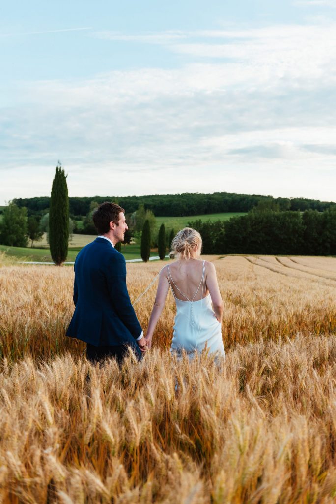 Couple walk together in the wheat fields for destination wedding photography France