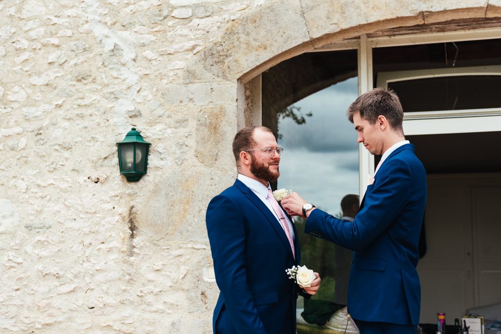 Groomsmen help each other with their button holes