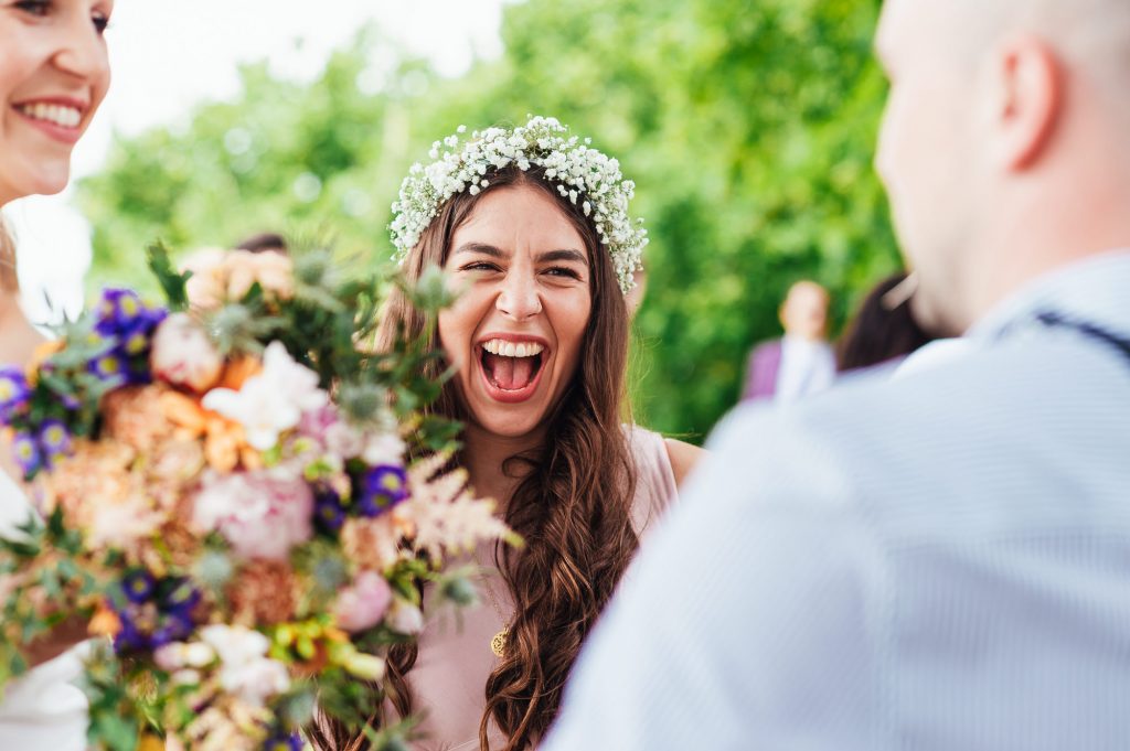 Gorgeous bridesmaid laughs with guest at romantic French outdoor wedding reception