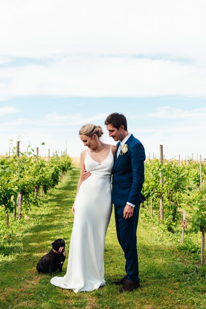 Vineyard wedding couples portrait with little pug dog