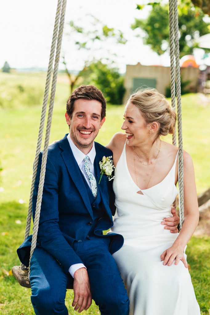 Cute couple sit together on a swing romantic wedding portrait
