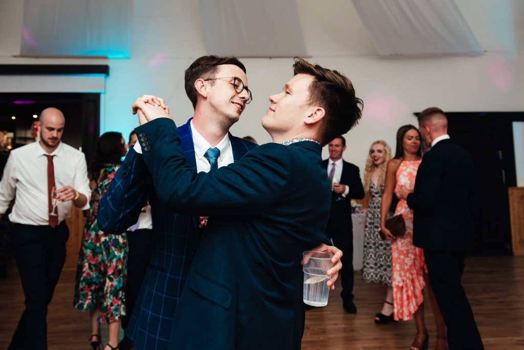 Two men dance together on a wedding dance floor