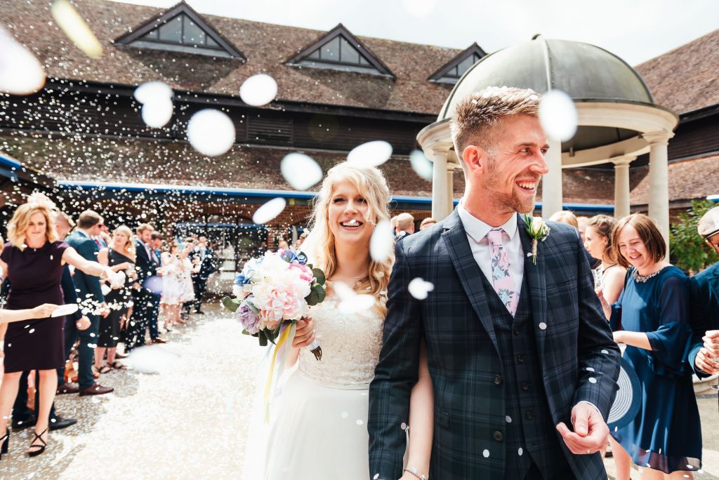 Young couple walk through a colourful confetti line at Denbies Wine Estate