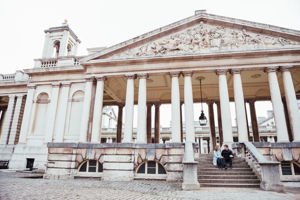 Couple sit at the steps of grand navel building in Greenwich for engagement photography shoot