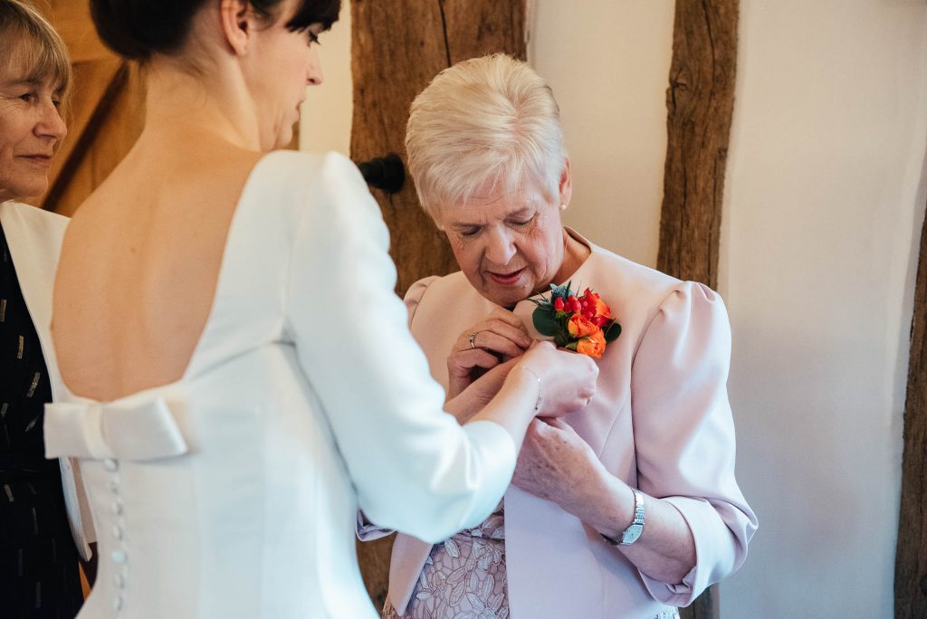 Bride pins on her mothers wedding corsage 