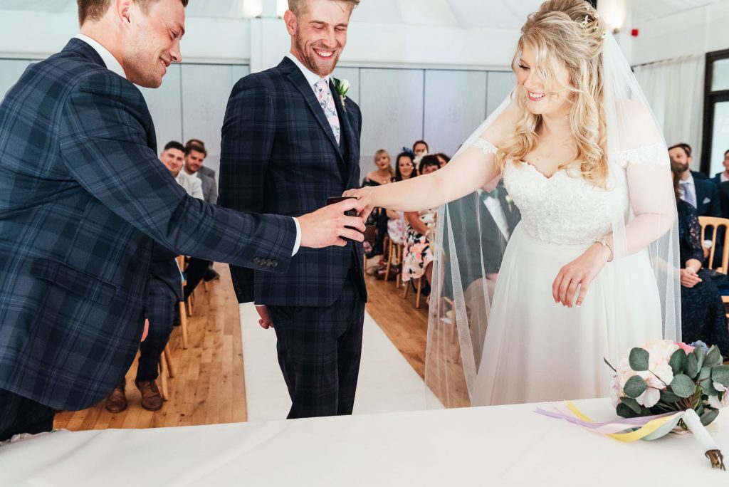 Best man hands the rings to the wedding couple