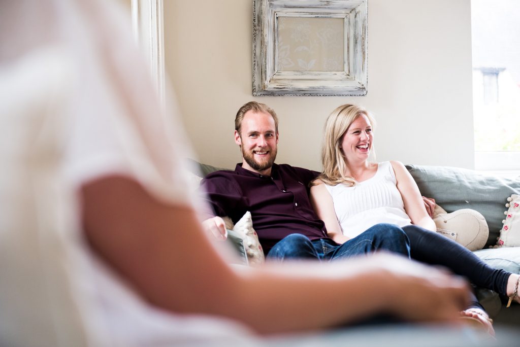 Couple sit together on sofa smiling