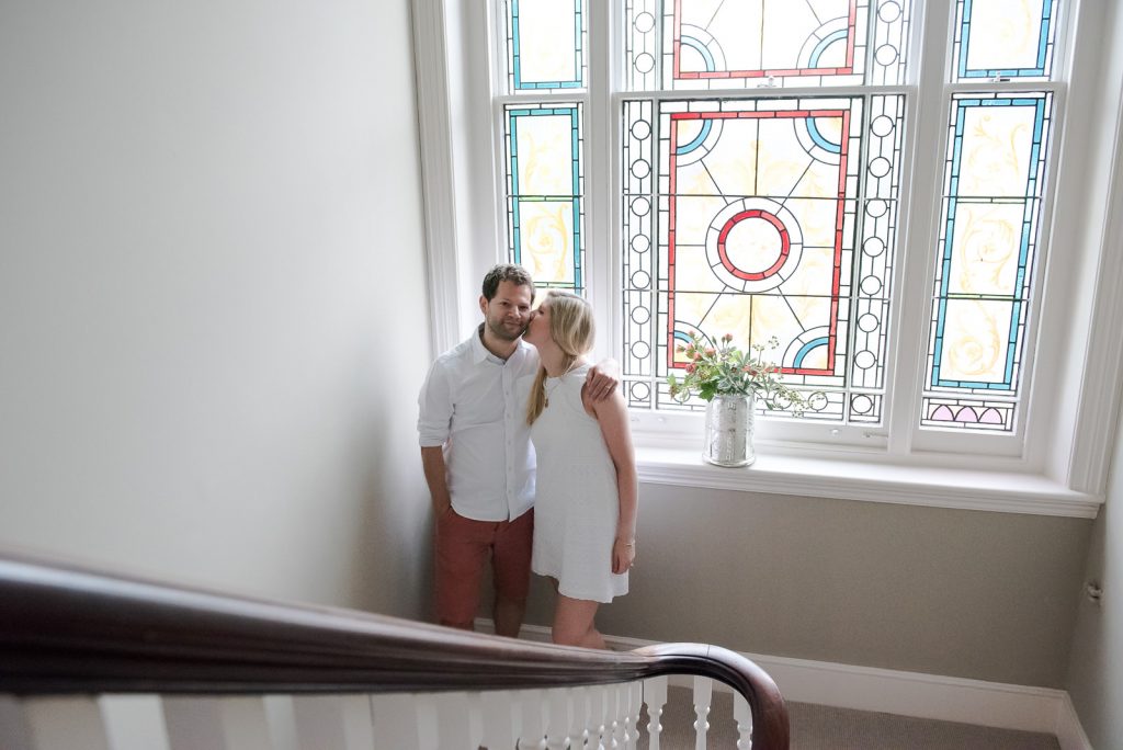 Couple stand on the stairs of their family home during London family shoot at home
