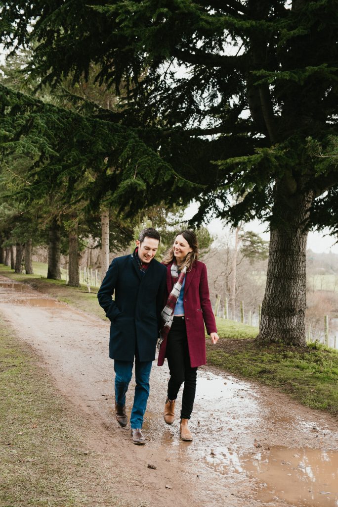 Couple walk together in the woods of Painshill Park