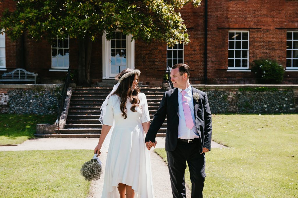 Newly married couple walk in the grounds of registry office together