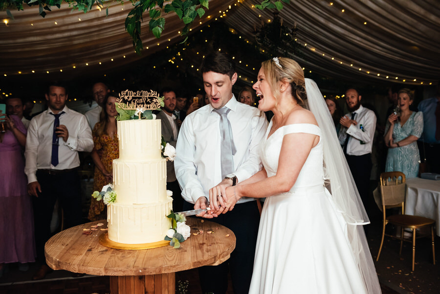Couple Cut The Wedding Cake - Outdoor Surrey Marquee Wedding