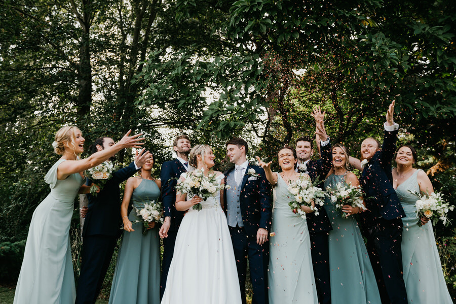 Wedding Party Throw Confetti Together in Candid Photograph