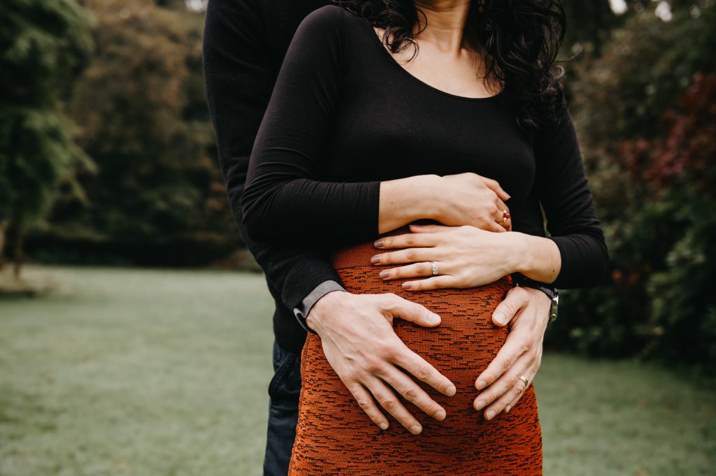 Mother and Fathers Hands Hold Baby Bump Together