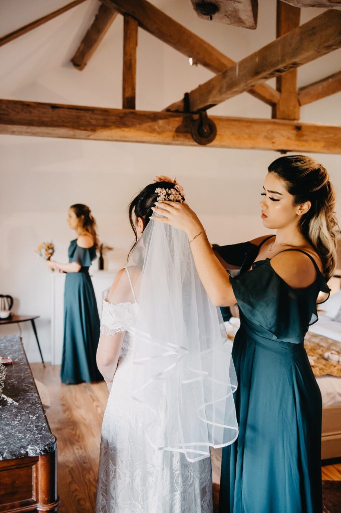 Sister helps the bride put on her wedding veil.