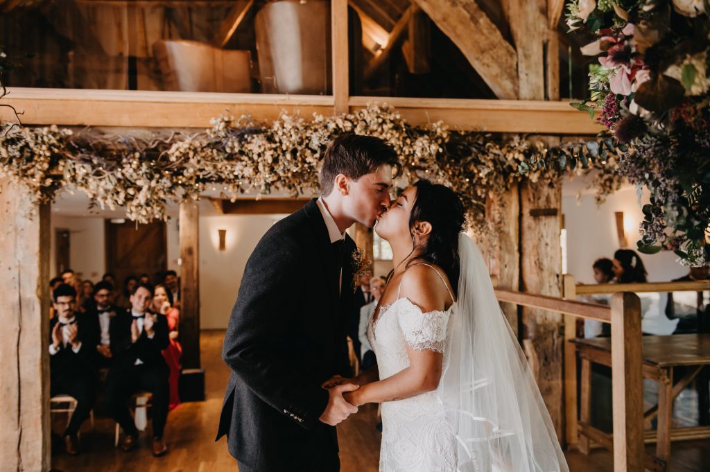 Couple share a first kiss after the ring exchange during wedding ceremony. 