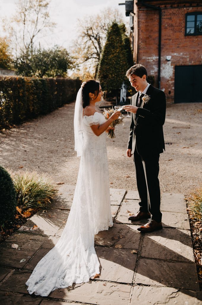 Couple share a moment with a glass of fizz together before the reception. 
