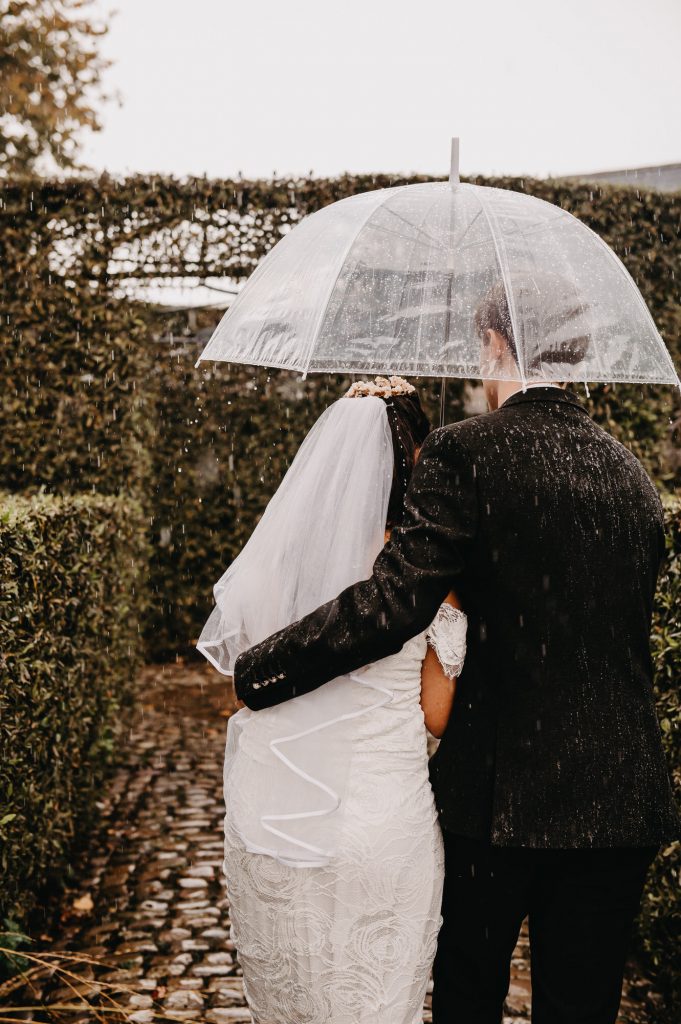 Couple Huddle Together under an Umbrella to Get Out Of The Rain. Documentary Wedding Photography - Surrey Wedding