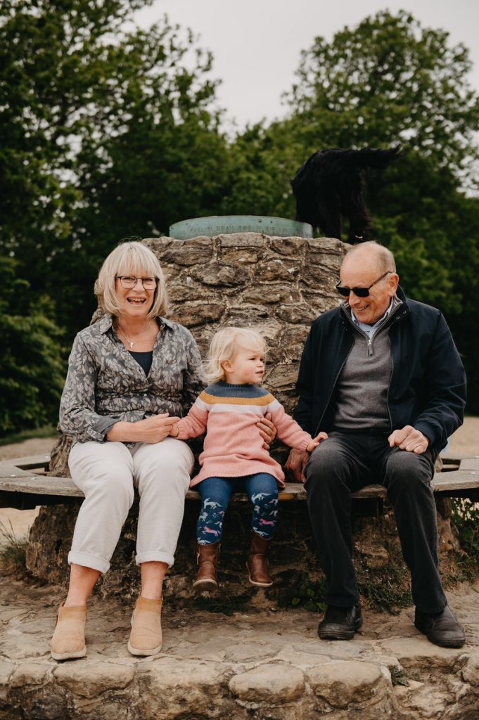 Grandparents and Granddaughter sit Together for Portrait - Holmbury Hill Family Photography