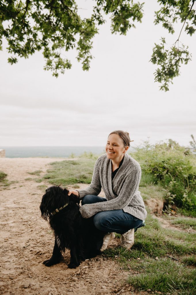 Woman kneels with family pet dog on outdoor family shoot - Holmbury Hill Family Photography